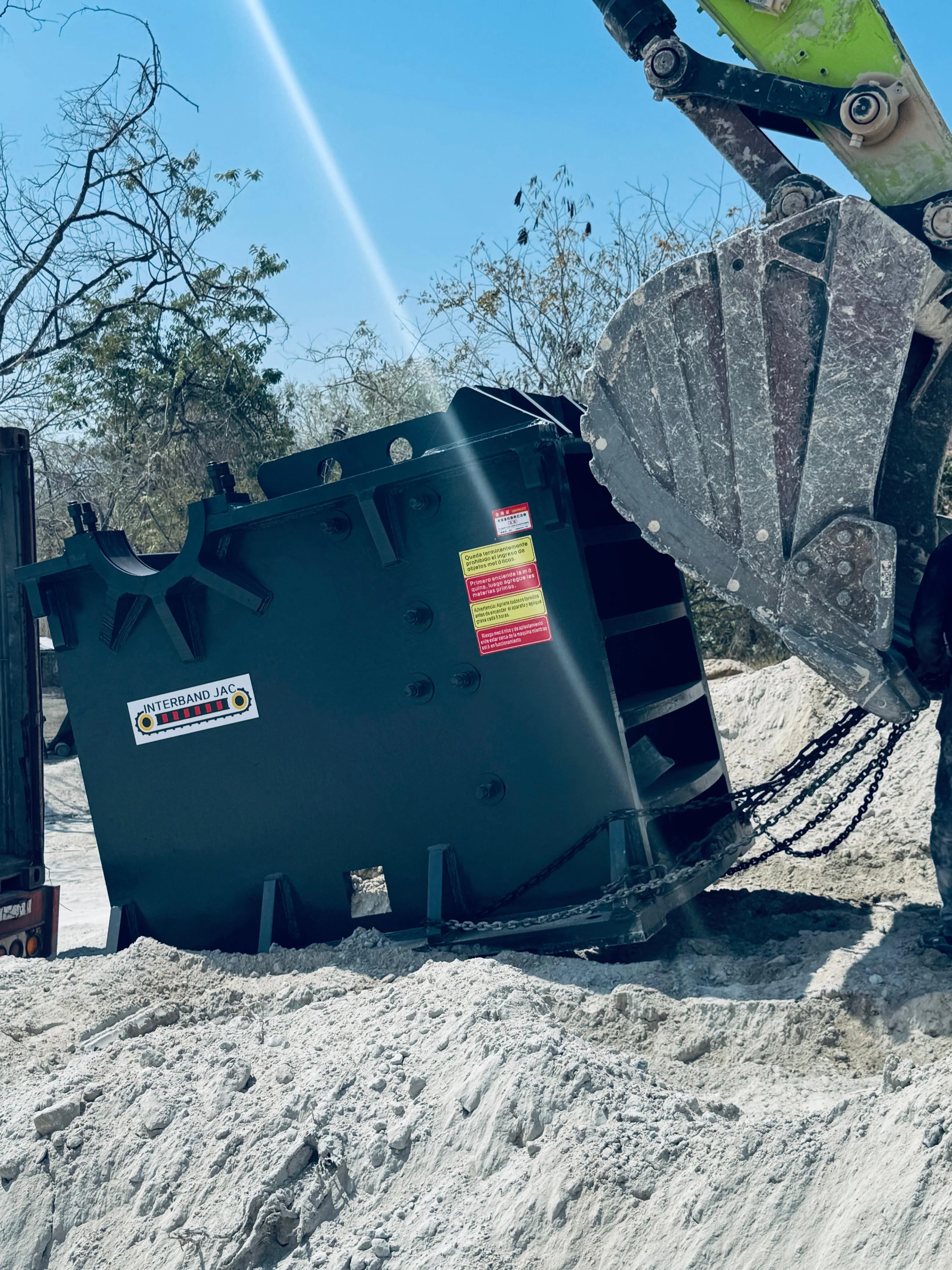 Descargue de trituradora con excavadora en sitio de obra